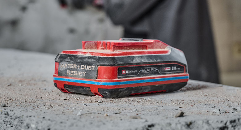 Einhell SEALED Power X-Change-batteri på en sten med støv.