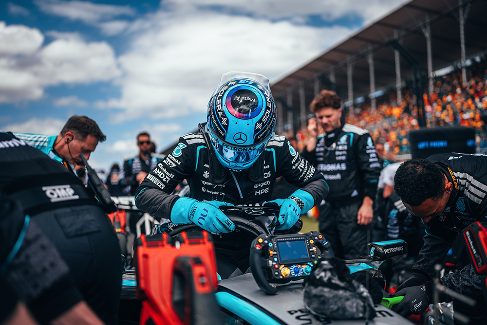 Formel 1-kører sidder i bilen omgivet af teamet på startgridden.