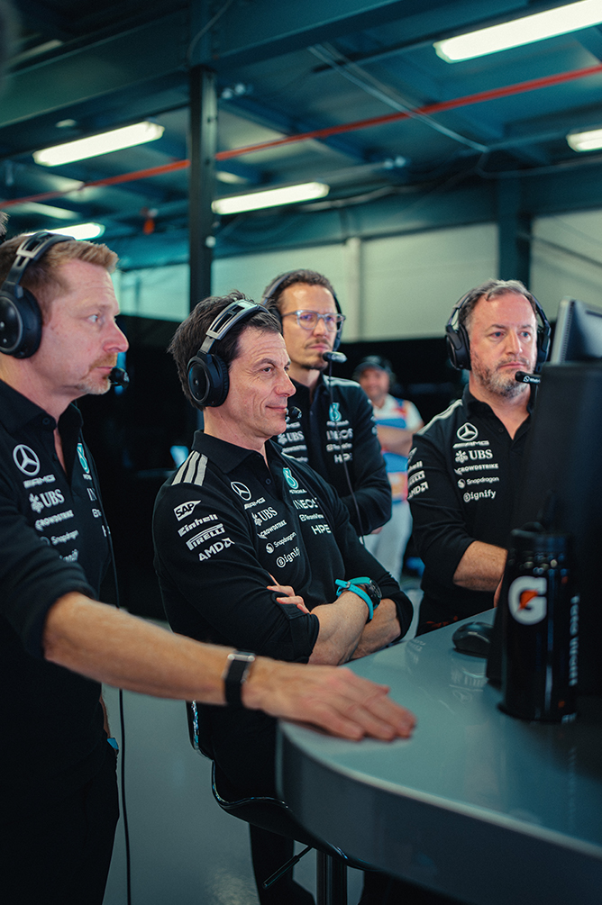 Formel 1-teammedlemmer med headset overvåger løbet fra pit wall