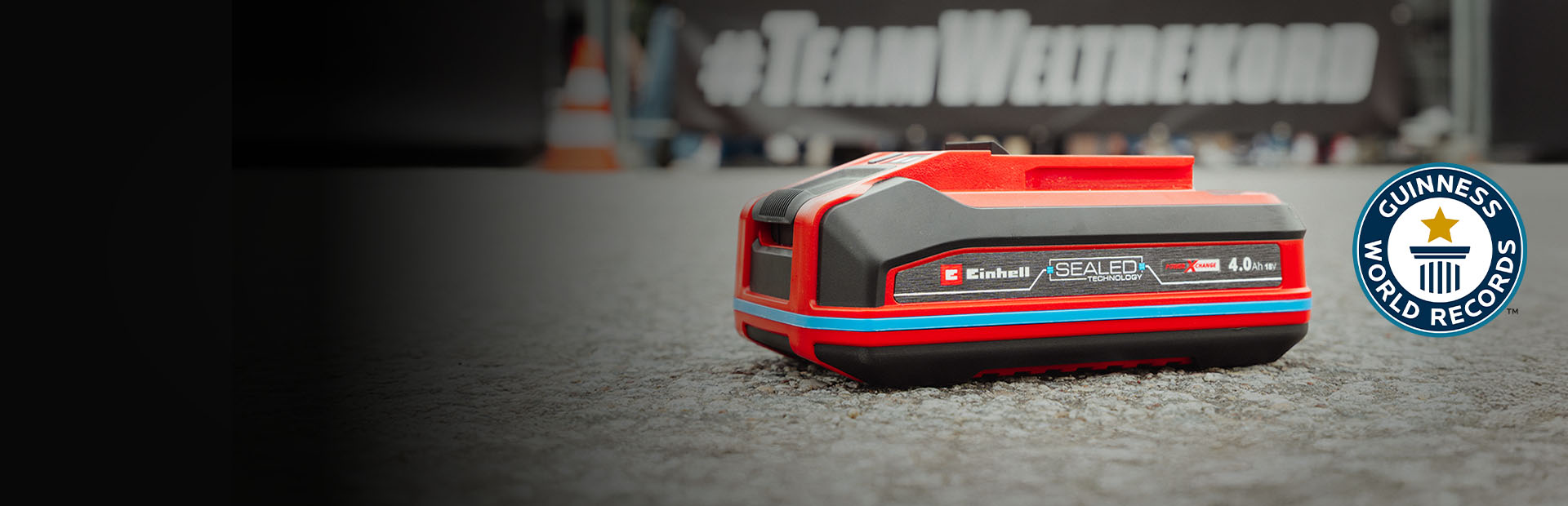 Einhell SEALED battery Power X-Change 4.0 Ah lies on asphalt, with the Guinness World Records logo on the right.