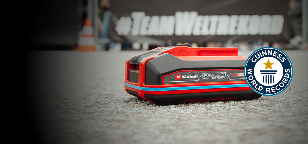 Einhell SEALED battery Power X-Change 4.0 Ah lies on asphalt, with the Guinness World Records logo on the right.